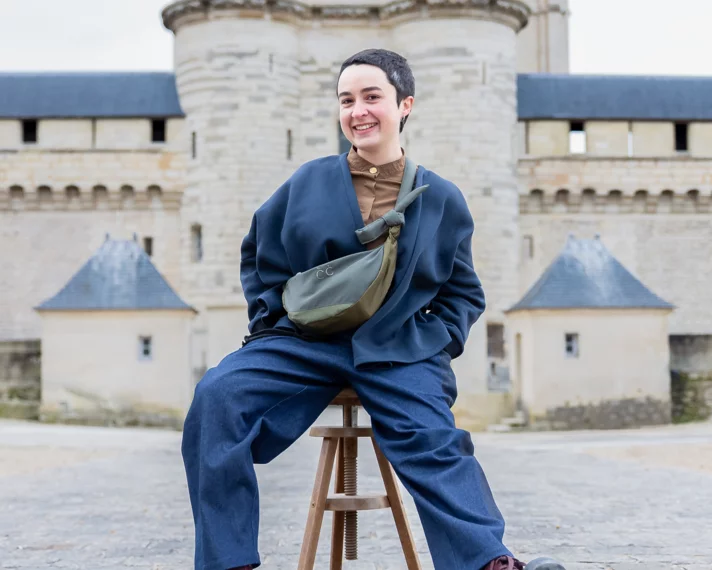 Armelle Antier assise sur un tabouret devant le donjon
